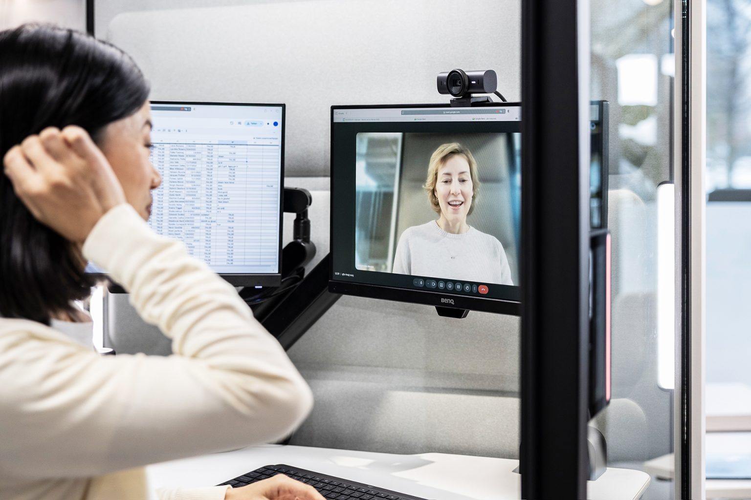 Employee on a video call at two monitors inside a Hushfree Work booth