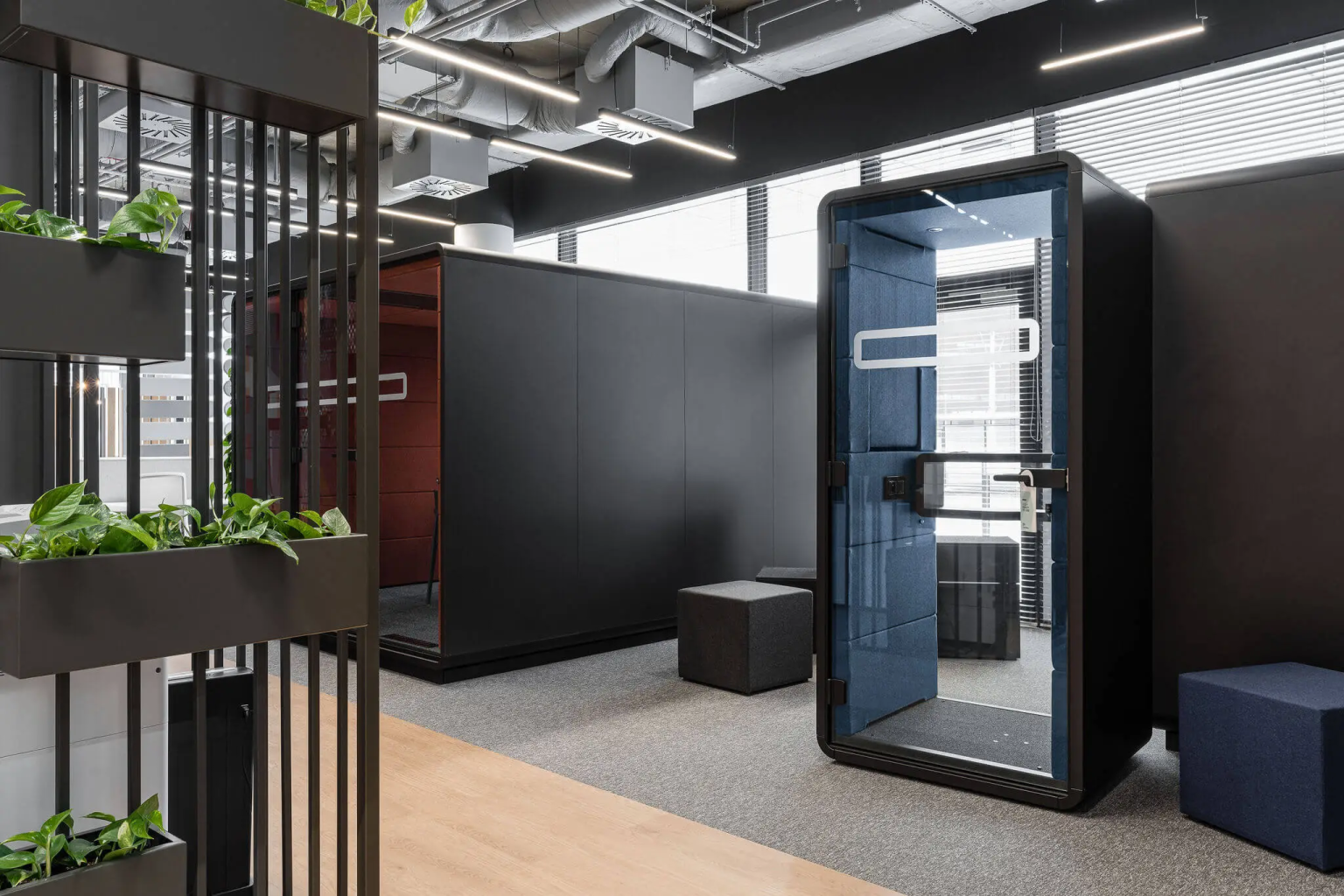 Black acoustic pods with planters on the coworking floor