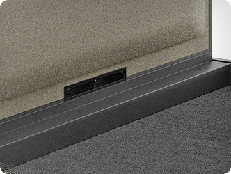 Floor-level ventilation opening integrated into the base of the office cubicle, visible as a structural detail near the carpet.