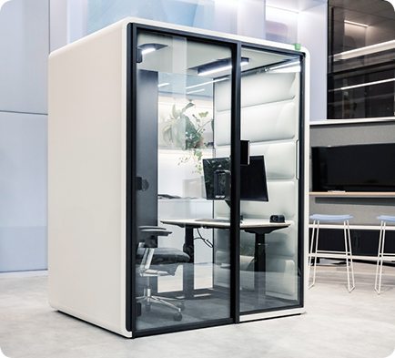 Kabina akustyczna Hushfree Work podczas wideokonferencji, z monitorem wyświetlającym rozmowę.