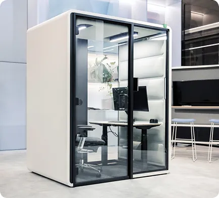 Kabina akustyczna Hushfree Work podczas wideokonferencji, z monitorem wyświetlającym rozmowę.